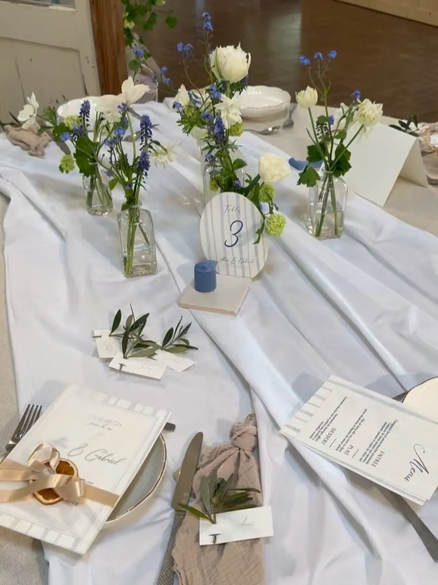 Table de mariage décorée de petits bouquets de fleurs de saison et de feuillage d'olivier